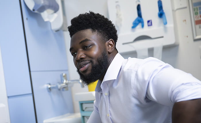 A student in a mock GP's consulting room, addressing someone out-of-frame
