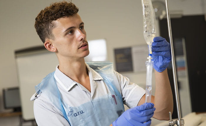 A Nursing student examining an IV drip bag on a stand