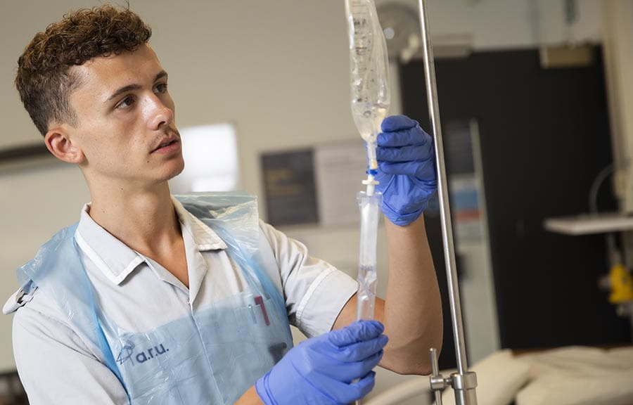 A Nursing student examining an IV drip bag on a stand