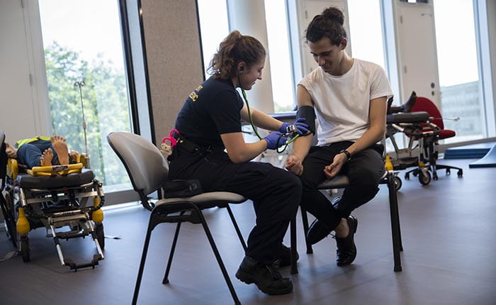 A Paramedic Science student practising taking another student's blood pressure in the skills lab
