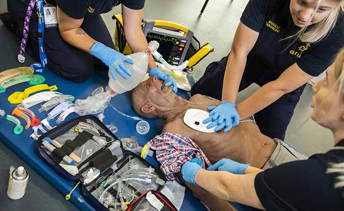 Three Paramedic Science students in the skills lab, practising resuscitation on a dummy