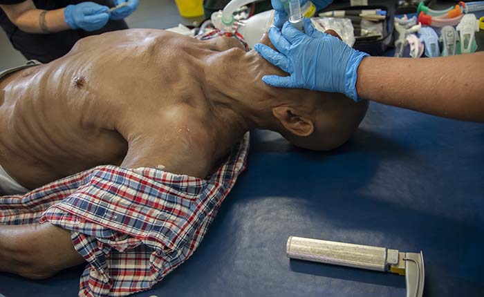 Hands of a Paramedic Science student practising intubating a dummy in the skills lab