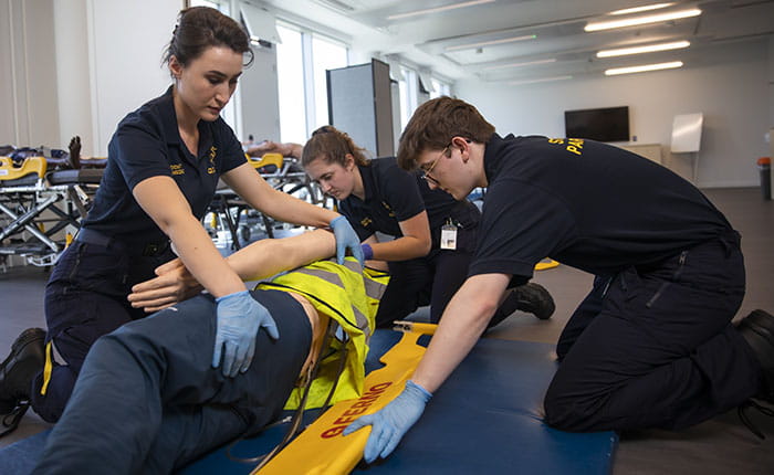 Three student paramedics practicing on a dummy