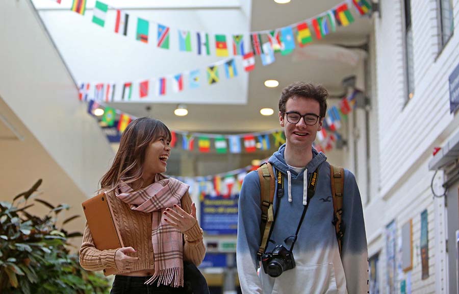 Two students walking inside a building decorated with country flag bunting