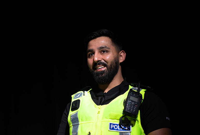 A police officer in high viz against a black background
