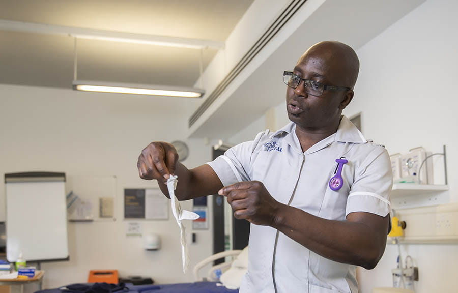 A student nurse preparing to put on surgical gloves in the skills lab 