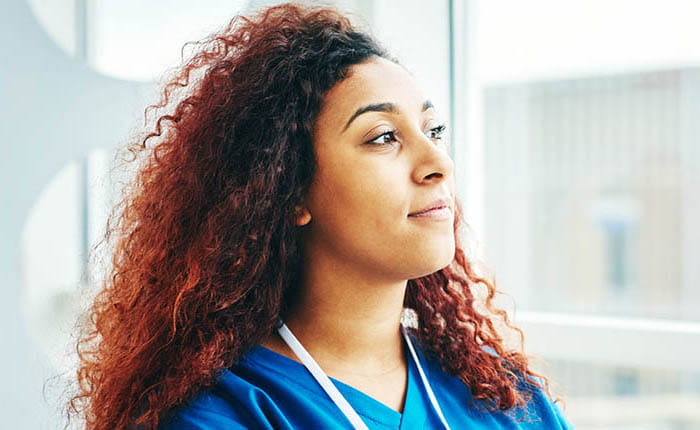 A nurse looking out of a hospital window pensively