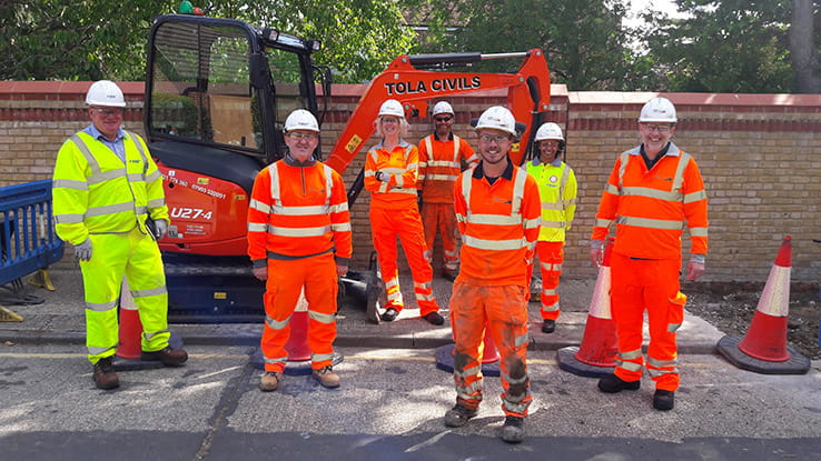 Staff from Ringway Jacobs and ARU in front of a digger, wearing high-viz suits