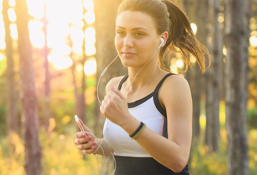 Someone jogging through trees, wearing headphones