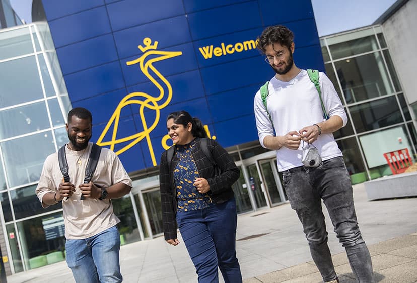Three students walking in front of the Lord Ashcroft Building on ARU's Chelmsford campus
