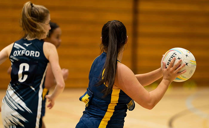 Back view of three students playing volleyball in the ARU sports hall