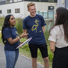 Two student ambassadors talking to a woman on ARU's Chelmsford campus