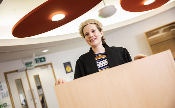A student at a podium wearing a barrister's wig