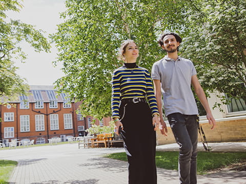A female and male student walk outside through the Cambridge campus