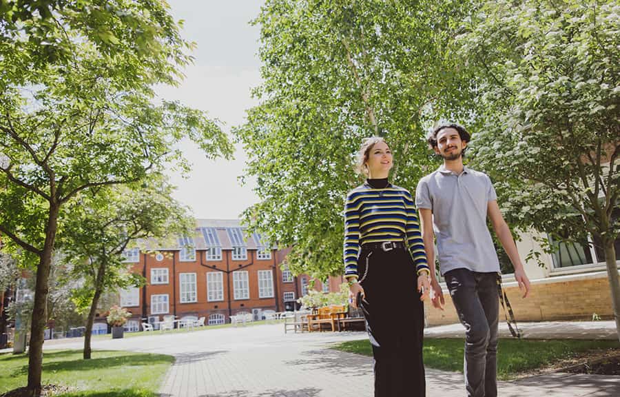 A female and male student walk outside through the Cambridge campus