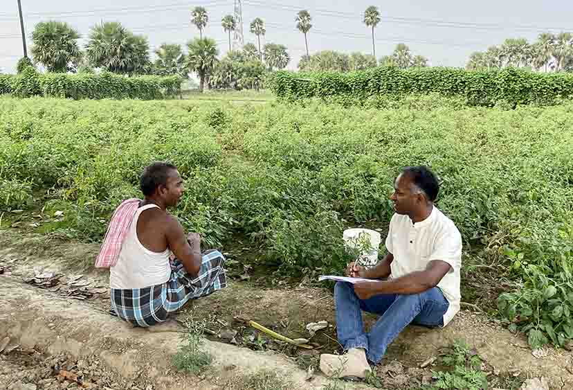 Prof Manoj Dora speaking to a vegetable farmer in a field in Naland, Bihar, India