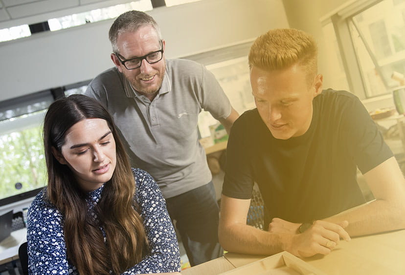 Two university students and a lecturer in a classroom