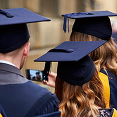 Three students wearing graduation gowns and mortar boards
