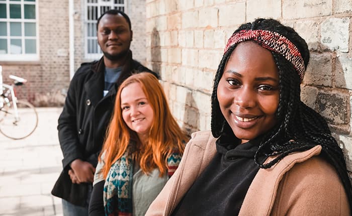 Three students pictured outside a university building
