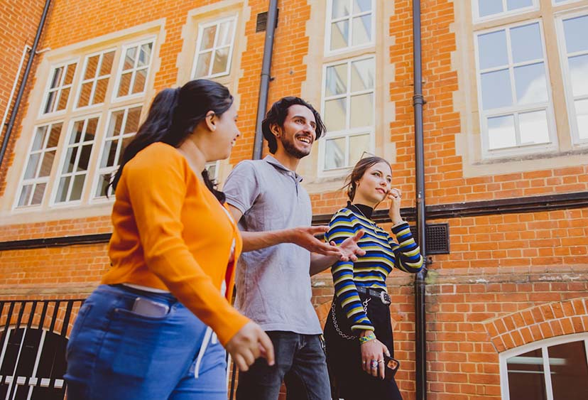 Three students walking past a university building