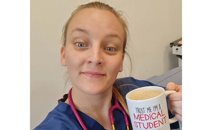 Medicine graduate Tina wearing scrubs and a stethoscope