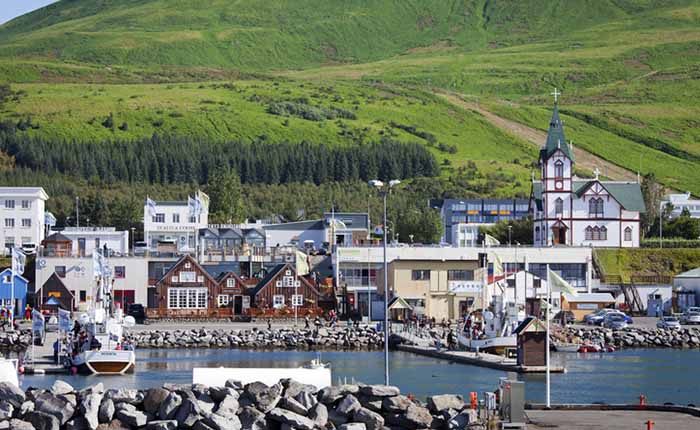 Scenic view of Husavik, Iceland, featuring a river port, buildings, and a mountain in the background