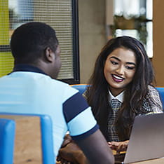 Two students working on a laptop together