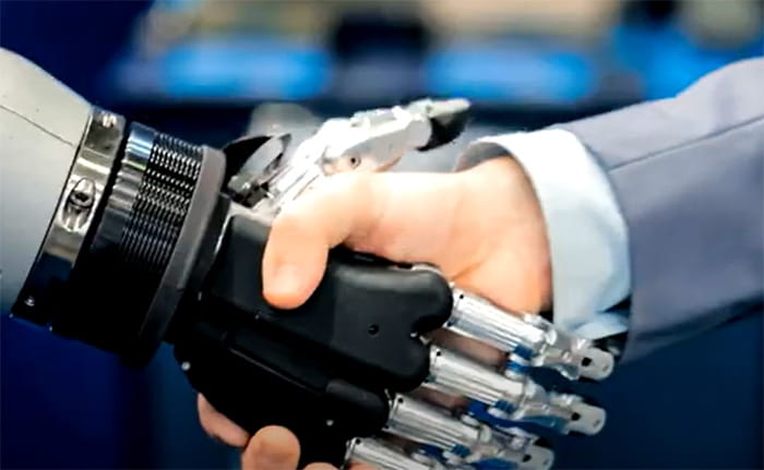 Video still of a human hand shaking with a robot hand