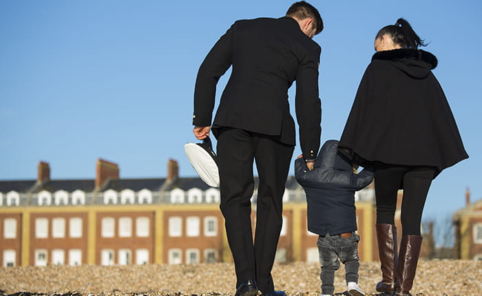 Back view of a male member of the armed forces walking with a woman and toddler