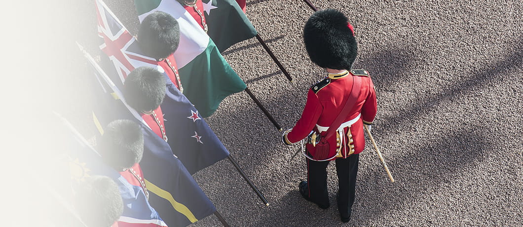 A row of Queen's Guards holding different flags, with one guard out in front