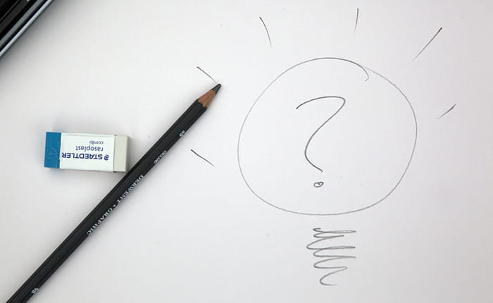 A pencil and rubber on a piece of paper with a question mark drawn on it