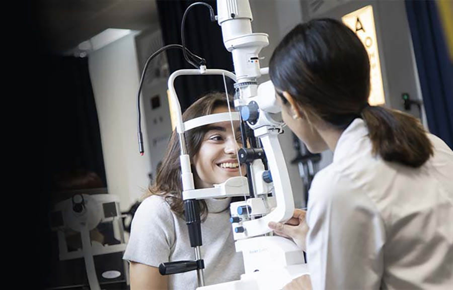 Two students using optometry equipment