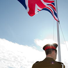 Back view of a soldier flying the Union Jack flag from a pole