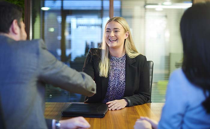 Woman sitting at a desk and shaking hands with an interviewer