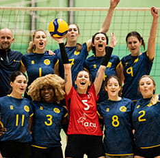 Members of a women's football team with hands raised in air in celebration