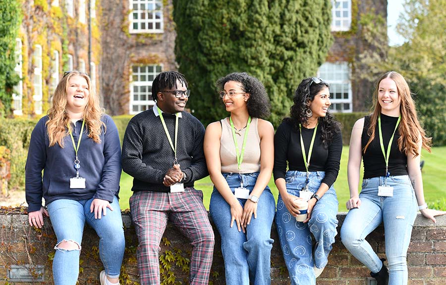 Five students sitting outside the main building on Anglia Ruskin University's Writtle campus