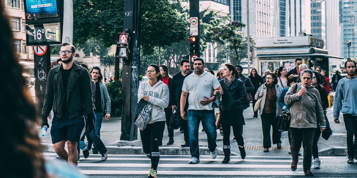 Lots of people walking across a busy zebra crossing