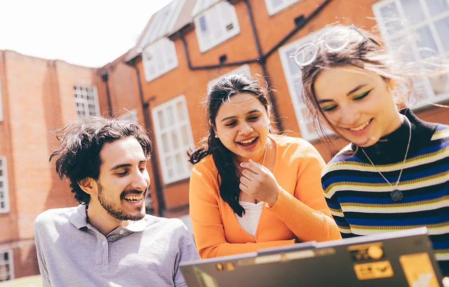 Three students in a courtyard outside a university building