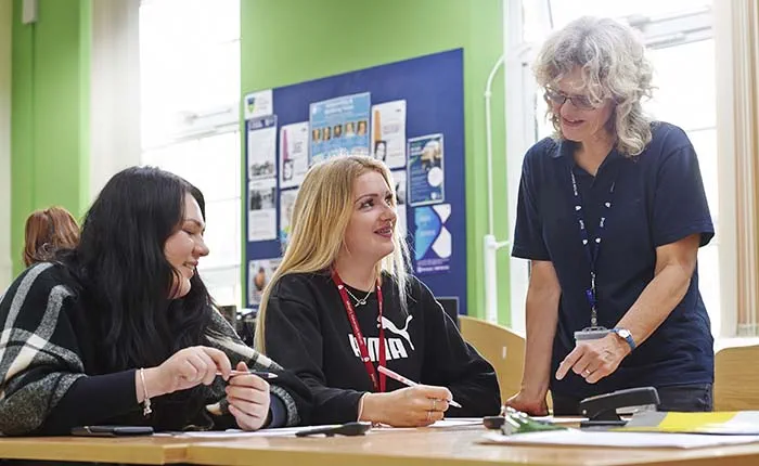Two college students with their tutor in a classroom