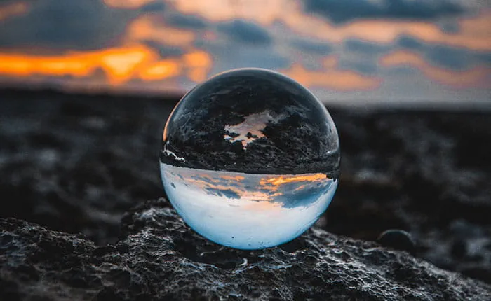 Glass globe on rocks, reflecting sky and sunset