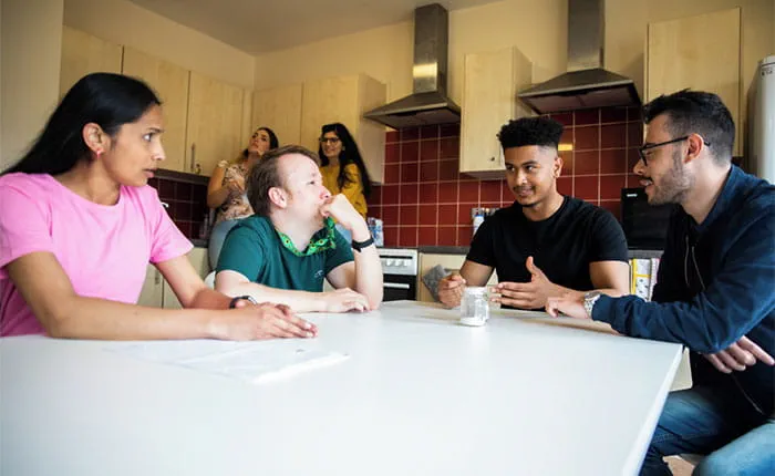 Students sitting around a table in a kitchen