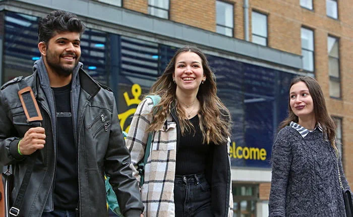 Three students outside the main entrance to ARU's Cambridge campus